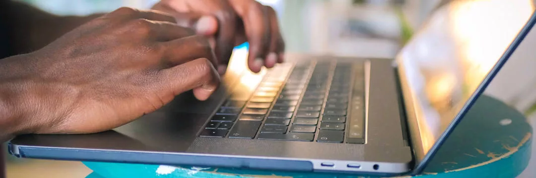 A person typing on a laptop, registering for VAT online