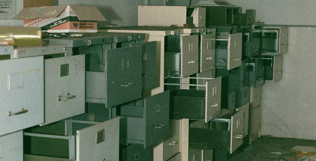 a bank of old grey filing cabinets with drawers open and empty