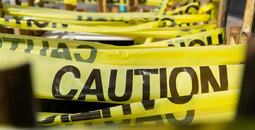 yellow caution tape strung back and forth across fenceline