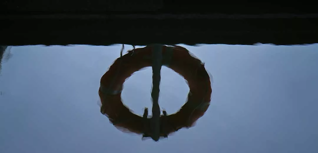 reflection of a rescue buoy in the water next to a dock