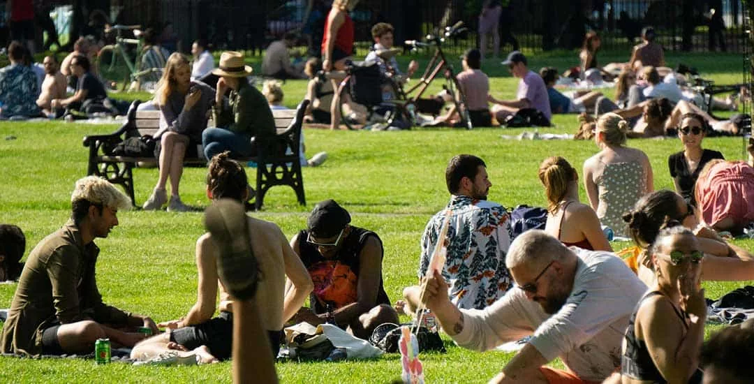large number of people in an english park enjoying the summer sun