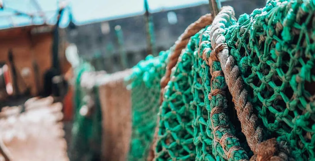 green fishing next hung over the side of a small fishing vessel