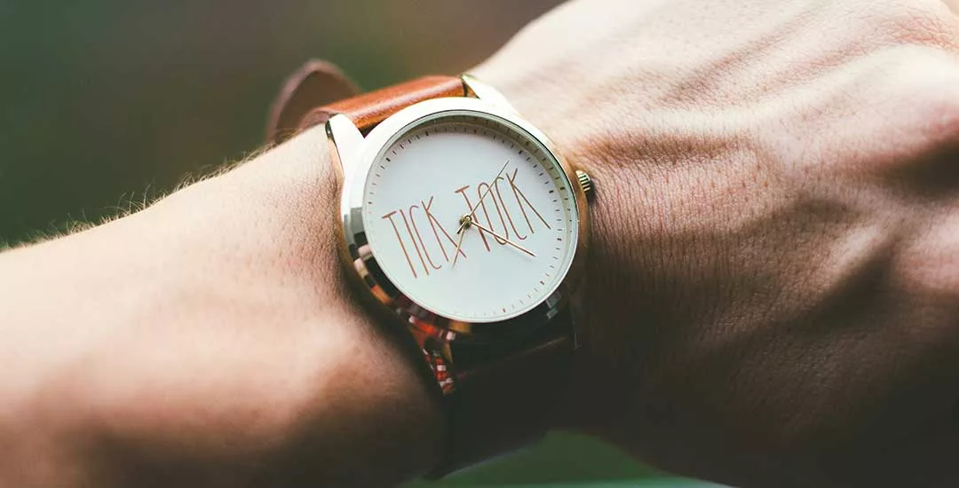 wrist wearing a watch with the words tick tock shown on the clock face