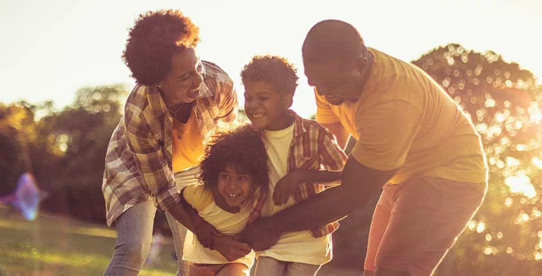 Family enjoying themselves at a park in the evening with sun behind them.