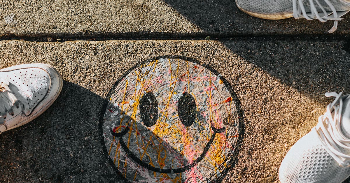 People standing around a smiley face drawn on the concrete.