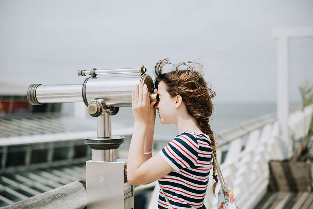 women looking through telescope on board walk