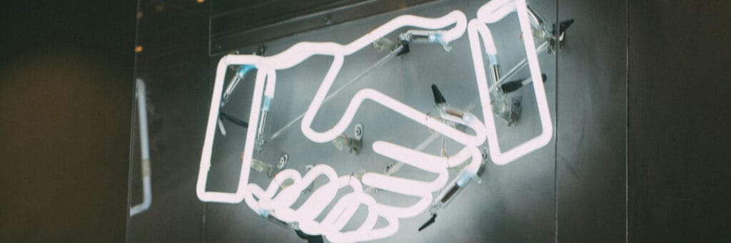 image of neon hands shaking representing the UK-Australia Double Tax Agreement.