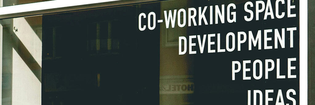 image of the window of a building that offers shared office space highlighting the benefits and drawbacks of dual employment.