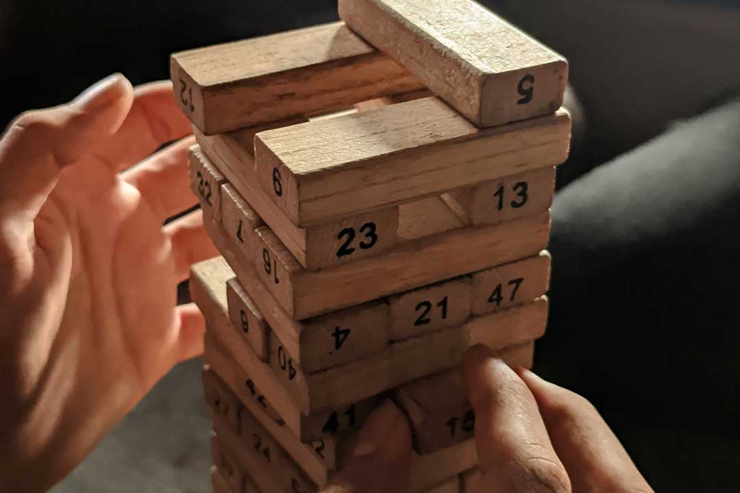 front on view of someone playing jenga with wooden blocks